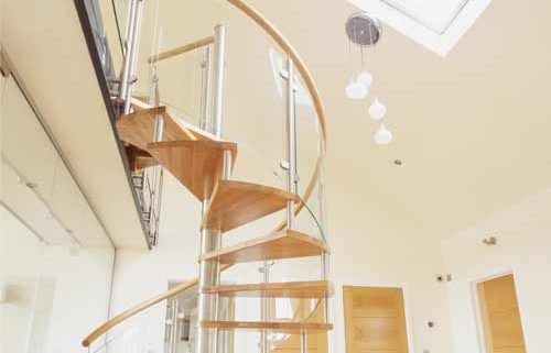 spiral stair leading up to a walkway beneath a roof window