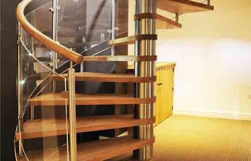 oak step spiral staircase with curved glass panels in a living area