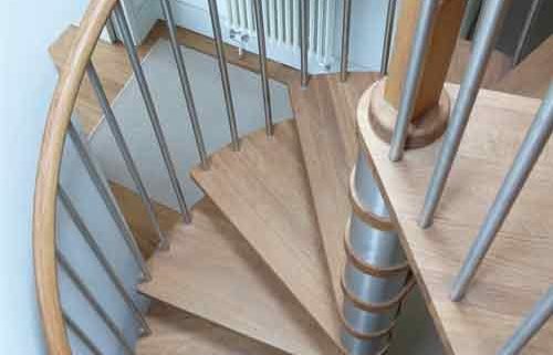 oak tread spiral staircase set within a circular opening with stainless spindles