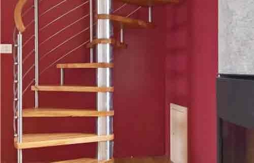 modern spiral staircase in front of dark red wall in a house