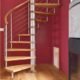 modern spiral staircase in front of dark red wall in a house
