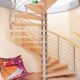 large light wood spiral staircase in a house with stainless steel horizontal bars