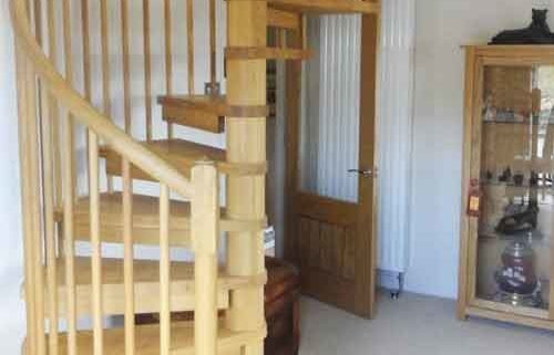 solid oak spiral staircase with timber spindles in a living room