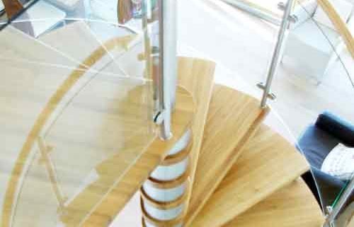 looking down on an oak spiral staircase with curved glass panels