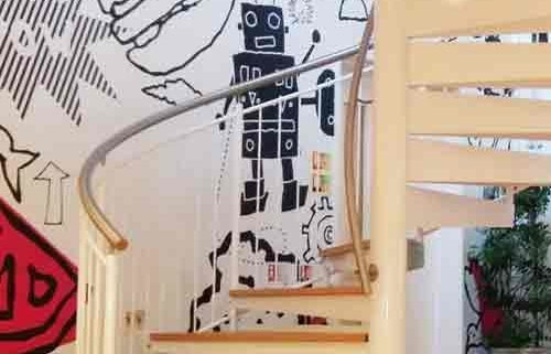 white steel spiral stair with oak steps in front of a funky wall