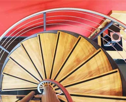 oak treads on a spiral stair with red wall to side