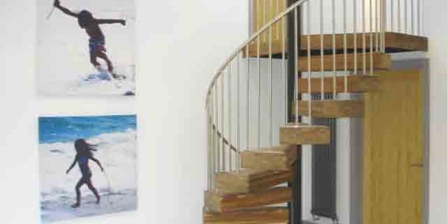 spiral stair with chunky walnut steps and stainless balustrade