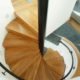 looking down on the oak steps of a spiral staircase with black wall mounted handrail