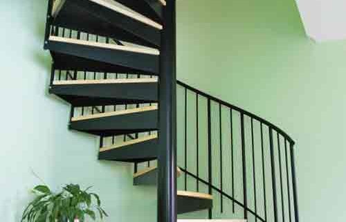 black spiral with timber steps in front of a green wall in a house