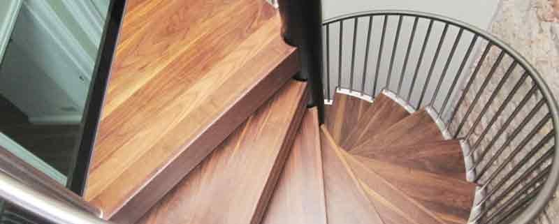 looking down on a walnut step spiral staircase alongside a glass floor