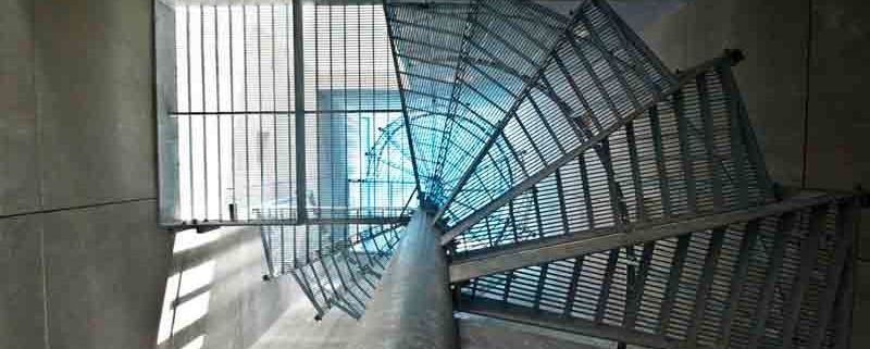 looking up through the perforated steel steps of a galvanised spiral staircase