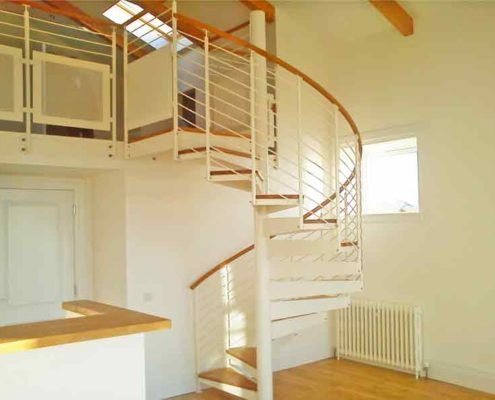 White spiral staircase with oak steps and handrail leading to mezzanine