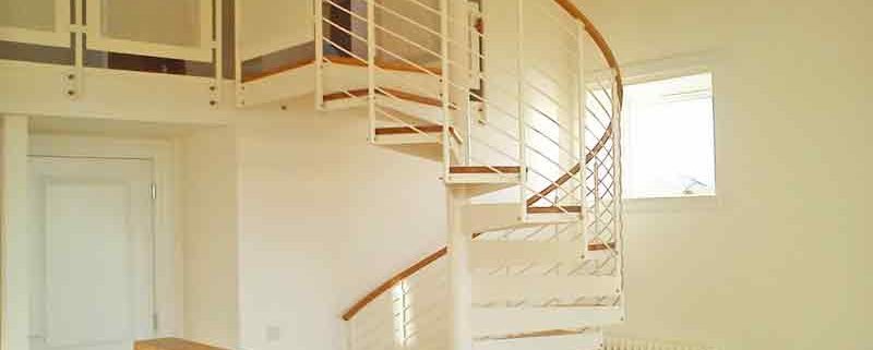 White spiral staircase with oak steps and handrail leading to mezzanine