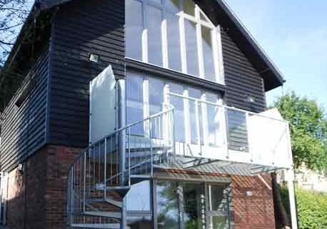 large steel balcony to side a black house with a spiral staircase
