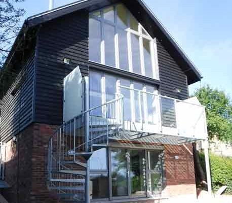 large steel balcony to side a black house with a spiral staircase