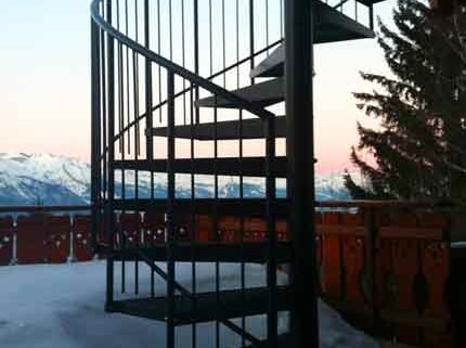 black outdoor spiral staircase with mountains to rear