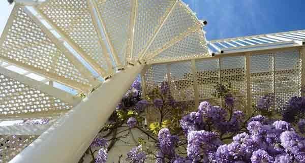 looking up at a white outdoor spiral stair with blue sky beyond