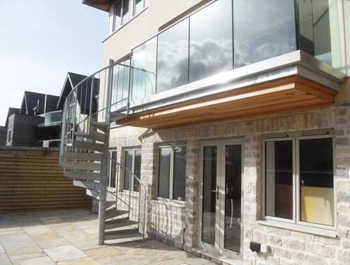 suspended balcony with frameless glass balustrade and a galvanised spiral staircase