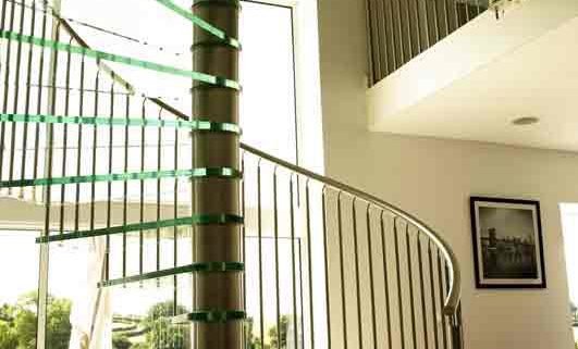 stainless steel handrail and spindles on a glass spiral stair in front of a window