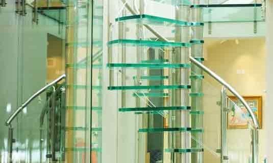 glass spiral staircase on tiled floor alongside a mirror