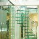glass spiral staircase on tiled floor alongside a mirror