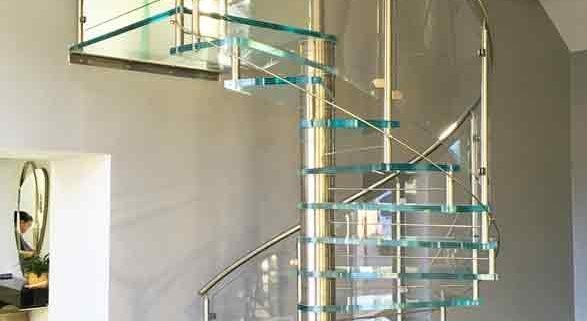 dark timber floor with a spiral stair with glass steps and curved glass panels