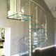 dark timber floor with a spiral stair with glass steps and curved glass panels