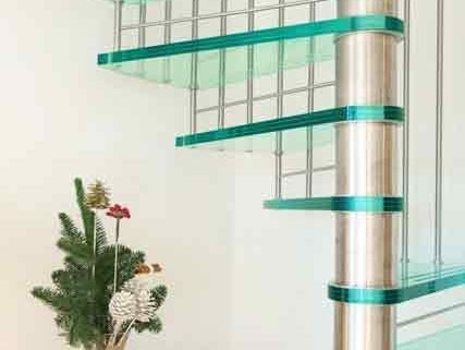 spiral staircase with glass steps and an oak sideboard