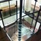 square glass platform at the top of a spiral stair with black balustrade