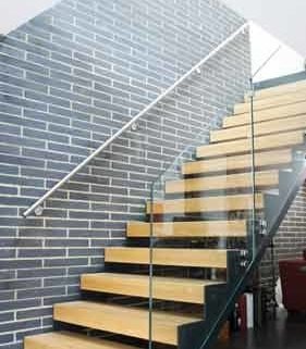 modern open riser stair in front of a brick wall