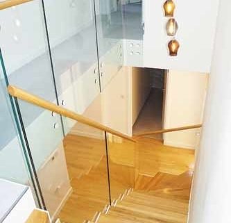 looking down an oak step stair with glass balustrade