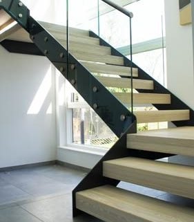 large black steel stringer stair with light timber steps and frameless glass
