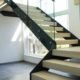 large black steel stringer stair with light timber steps and frameless glass