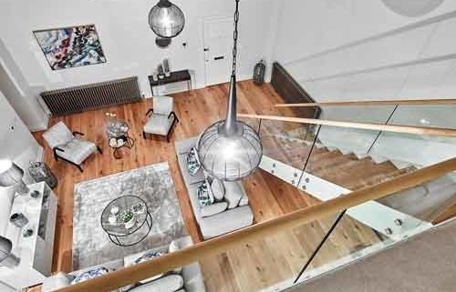 looking down on a living area with wood floor and modern staircase