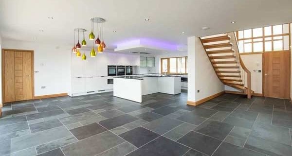large grey tiled living area with kitchen and modern stair on show