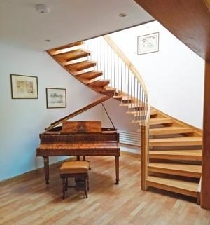 curved wooden staircase with piano