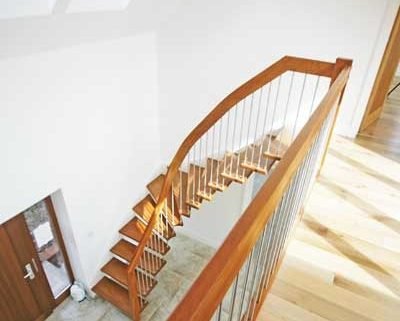 looking down on hallway with a beech floating staircase in front of a white wall