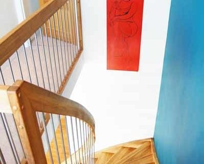 white wall with red picture and blue wall alongside an oak staircase