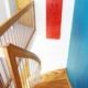 white wall with red picture and blue wall alongside an oak staircase