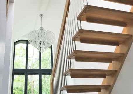huge hallway featuring a straight flight wooden staircase with large window behind