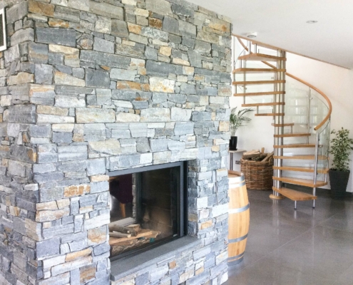 large dry stone wall with fireplace with barrel and spiral staircase