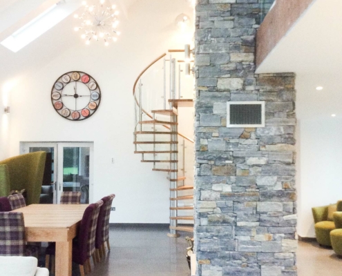 intricate stone wall and dining table and spiral stair beyond