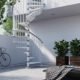 white outdoor spiral stair running up side of white rendered house