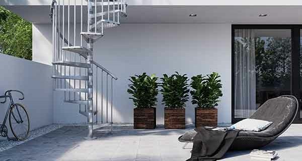 Exterior-Zink-Spiral-Staircase running up the side of a house with sun lounger on patio