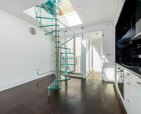 kitchen setting with dark floor and white walls and a glass spiral staircase