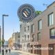 Project of the month promotional image with company logo and the background of a street in Shoreditch