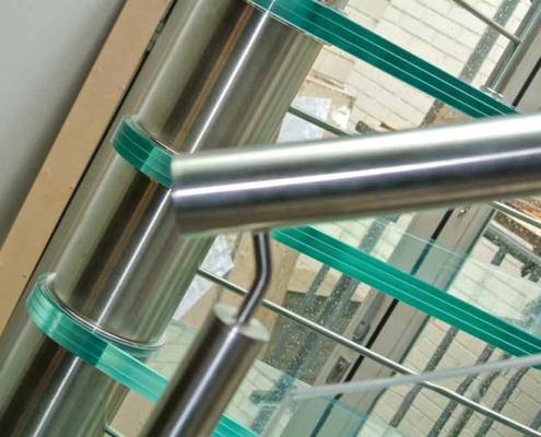 Zoom on a stainless steel handrail on a spiral staircase with glass steps