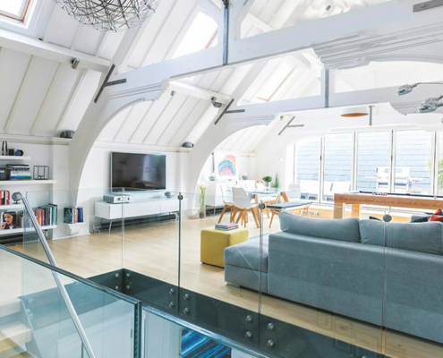 large open living space under a large vaulted ceiling. sofa and modern staircase in the foreground