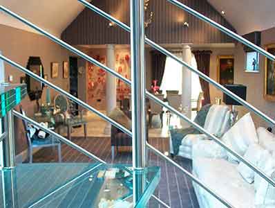 chairs and sofa in living room behind with close up of a glass step on a spiral stair in foreground