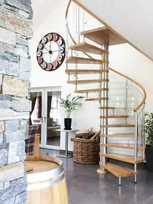 spiral stair with curved glass panels and oak tread with a clock on the wall